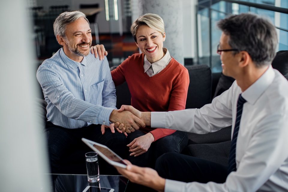 couple shaking hands with financial adviser