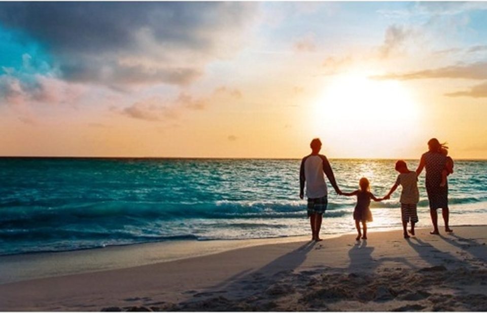 Family walking on beach at sunset